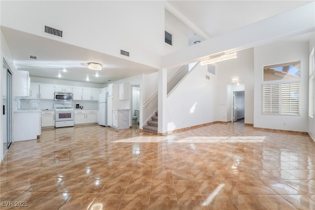 unfurnished living room featuring a towering ceiling