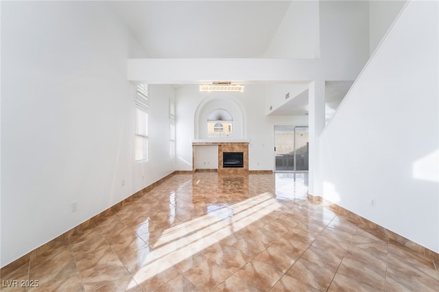 unfurnished living room with a tile fireplace and a towering ceiling