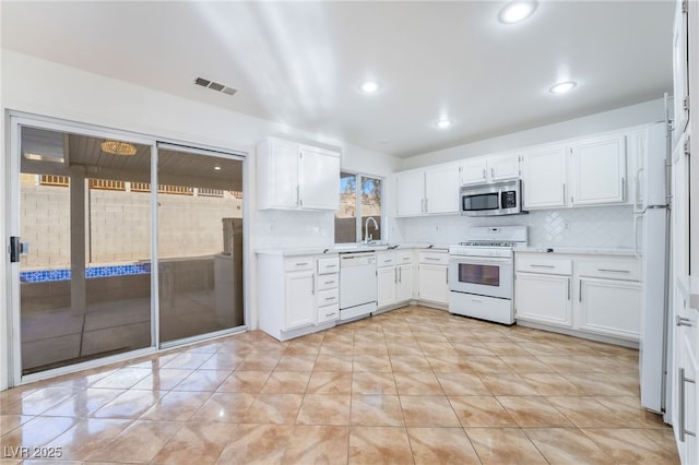 kitchen featuring white cabinetry, sink, white appliances, and decorative backsplash