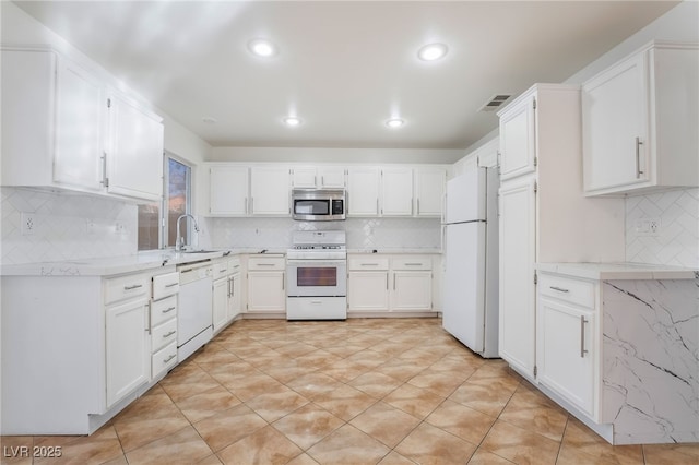 kitchen with tasteful backsplash, white appliances, sink, and white cabinets