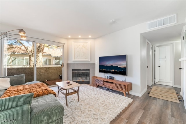 living room featuring a tile fireplace and wood-type flooring