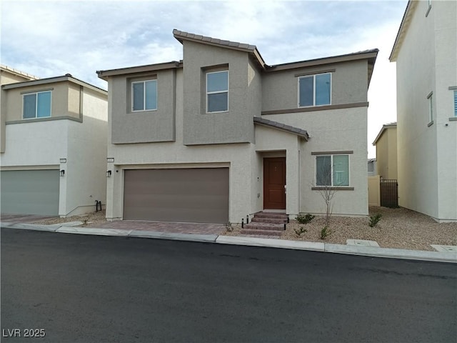 view of front of home featuring entry steps, a garage, a tiled roof, decorative driveway, and stucco siding