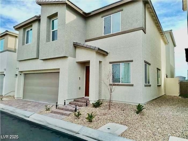 view of front of home with an attached garage, fence, and stucco siding