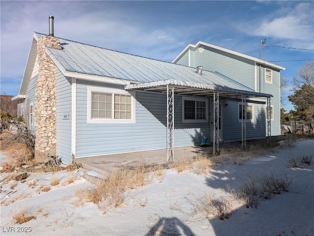 view of front of house featuring metal roof and a chimney