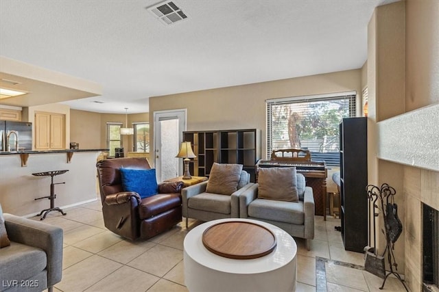 living room with a tiled fireplace, light tile patterned floors, and a healthy amount of sunlight