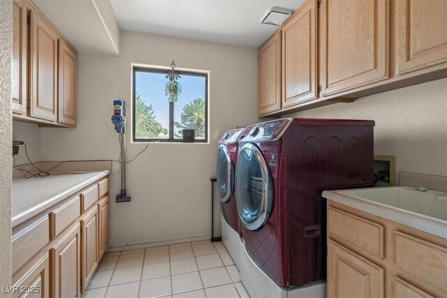 washroom with cabinets, light tile patterned floors, and washing machine and clothes dryer