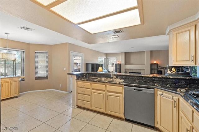 kitchen with decorative light fixtures, sink, dark stone countertops, stainless steel dishwasher, and light brown cabinets