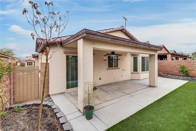 back of property with a ceiling fan, a patio area, fence, and stucco siding