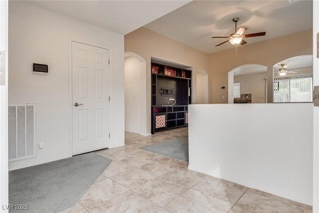 kitchen with arched walkways, visible vents, built in shelves, and ceiling fan