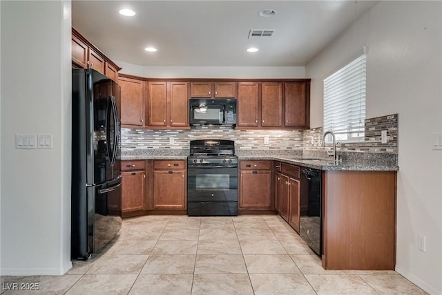 kitchen featuring dark stone countertops, visible vents, a sink, black appliances, and tasteful backsplash