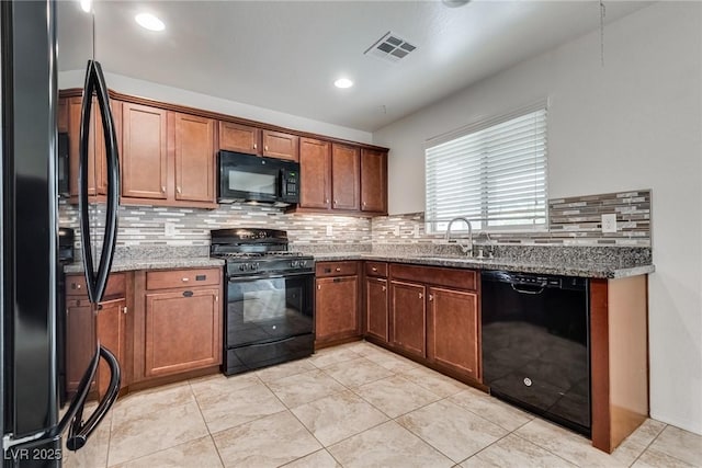 kitchen with visible vents, stone countertops, a sink, black appliances, and backsplash