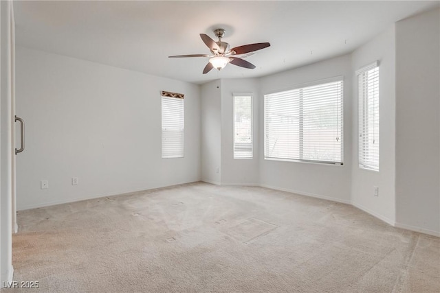 unfurnished room with plenty of natural light, light colored carpet, and ceiling fan