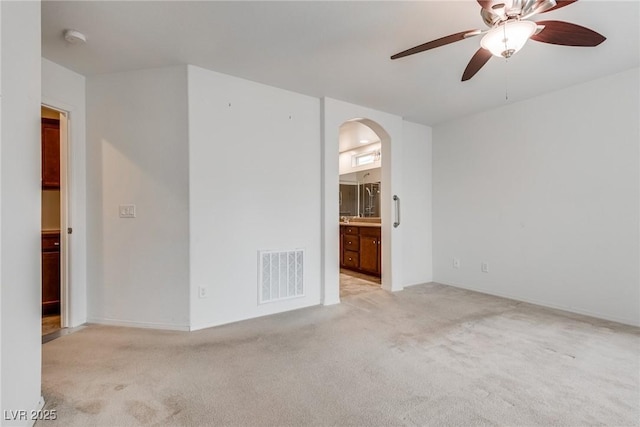 unfurnished room featuring visible vents, arched walkways, light carpet, and a ceiling fan