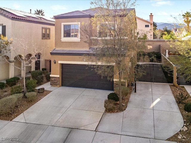 mediterranean / spanish-style house with a garage, concrete driveway, a gate, and stucco siding