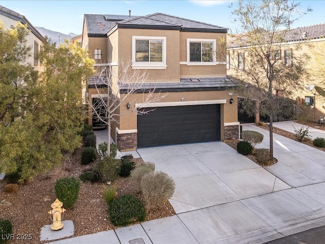 view of front of property featuring an attached garage, stone siding, concrete driveway, and stucco siding