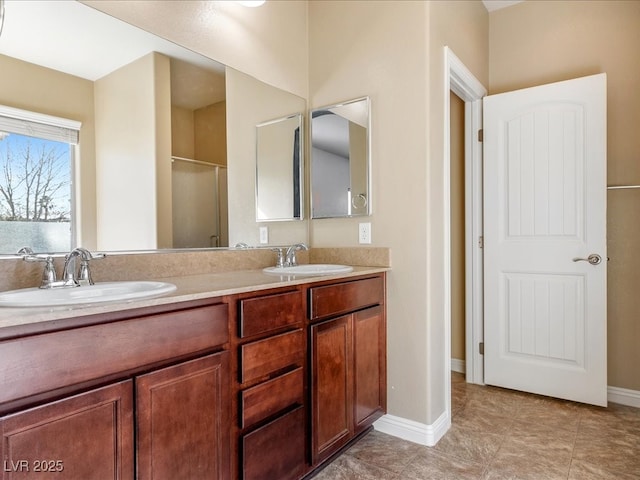 full bathroom featuring double vanity, an enclosed shower, a sink, and baseboards