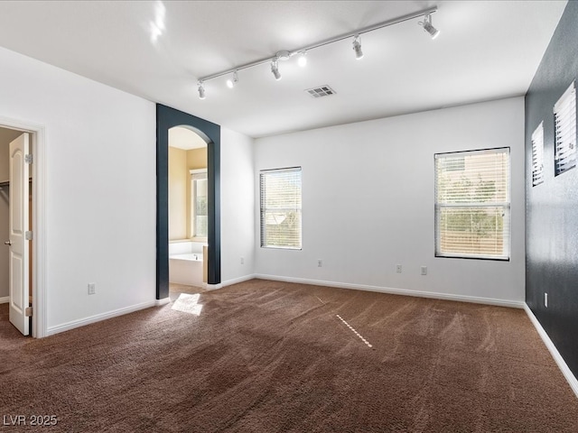 unfurnished bedroom with arched walkways, carpet floors, and baseboards