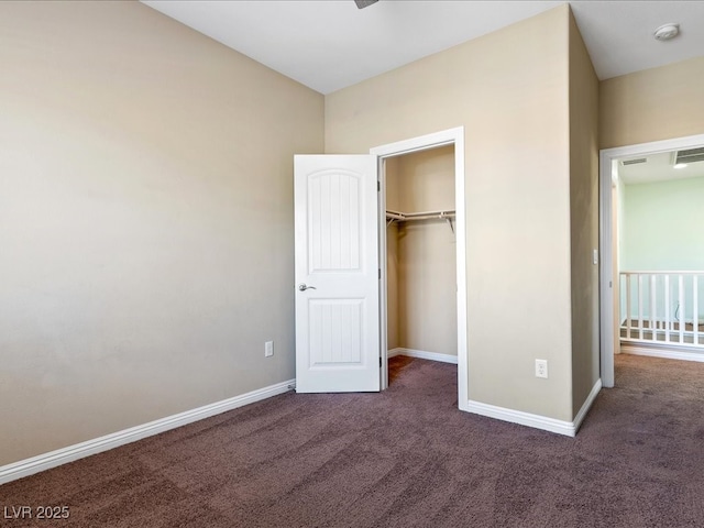 unfurnished bedroom with carpet floors, a spacious closet, a closet, and baseboards