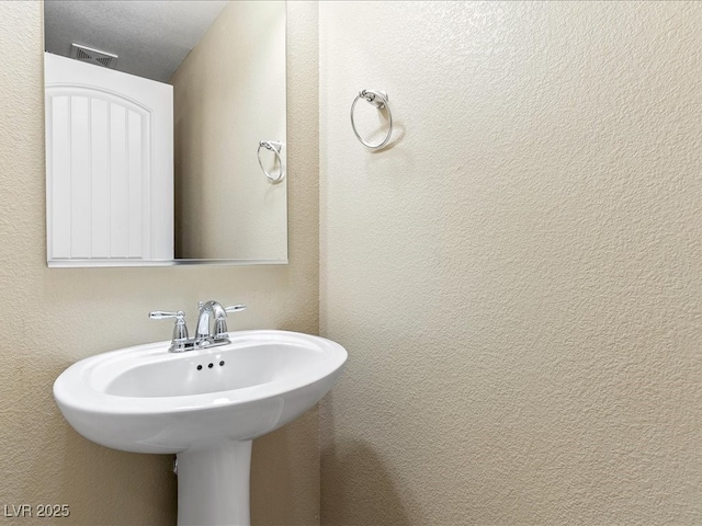 bathroom with a textured wall and visible vents