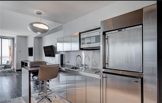 4381 W Flamingo Rd Unit 3007, Las Vegas, NV 89103 - kitchen featuring modern cabinets, a sink, stainless steel countertops, stainless steel microwave, and wood finished floors