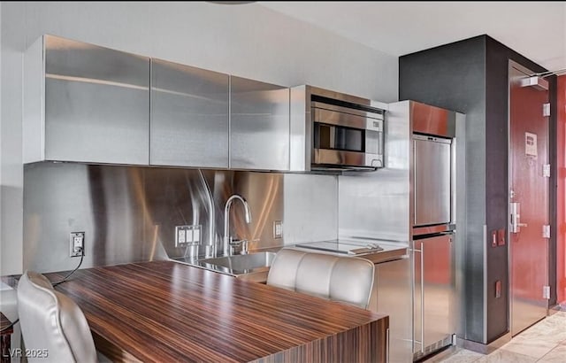 4381 W Flamingo Rd Unit 3007, Las Vegas, NV 89103 - kitchen with modern cabinets, a sink, stainless steel microwave, electric stovetop, and paneled built in fridge