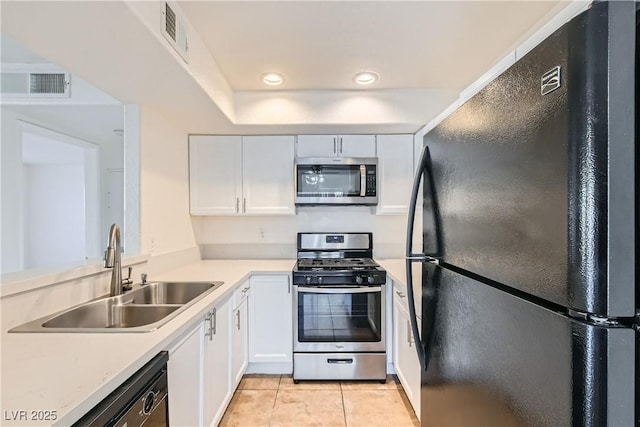 kitchen with sink, light tile patterned floors, white cabinets, and black appliances