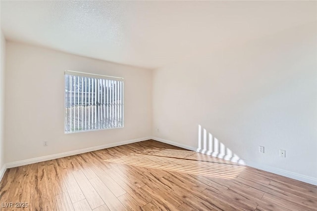 spare room with a textured ceiling and light wood-type flooring