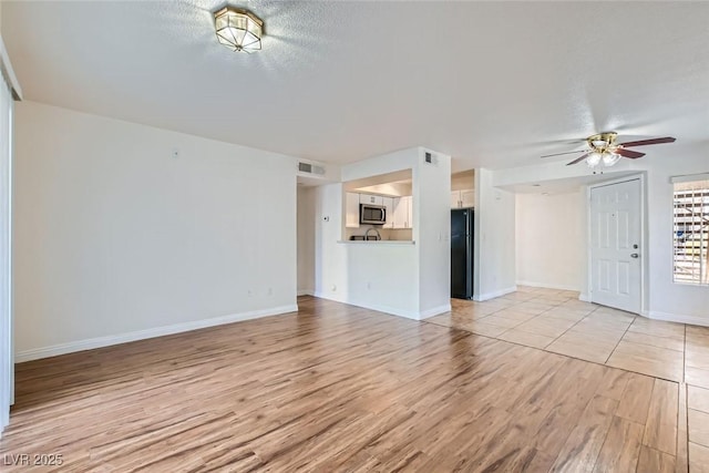 unfurnished living room featuring ceiling fan, light hardwood / wood-style flooring, and a textured ceiling