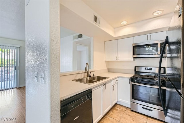 kitchen with sink, light tile patterned floors, white cabinets, and black appliances