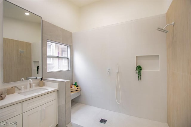 bathroom with a tile shower and vanity