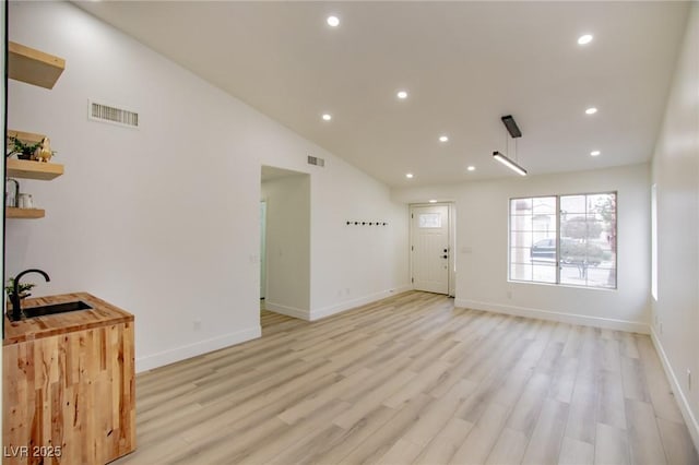 living area with recessed lighting, visible vents, light wood finished floors, and baseboards