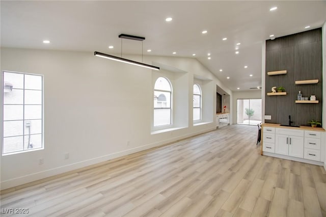 kitchen with light wood-type flooring, open floor plan, recessed lighting, white cabinets, and vaulted ceiling