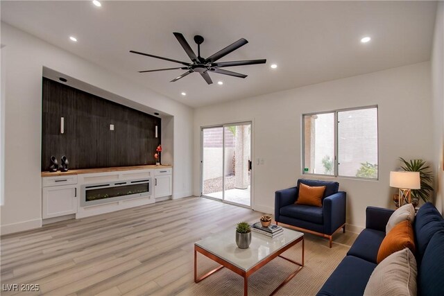 living room with light wood-style flooring, a ceiling fan, recessed lighting, a fireplace, and baseboards