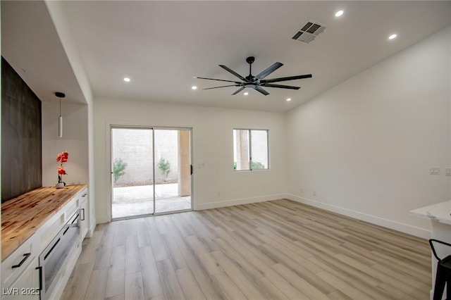 unfurnished living room with recessed lighting, light wood-type flooring, and baseboards