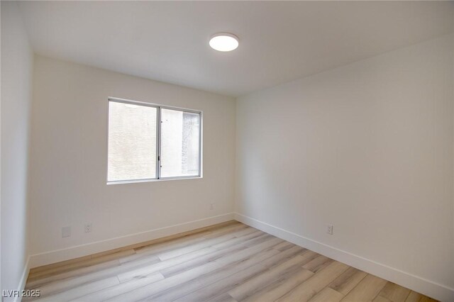 empty room featuring light wood finished floors and baseboards