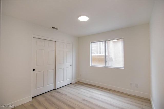 unfurnished bedroom with a closet, visible vents, baseboards, and light wood-style floors