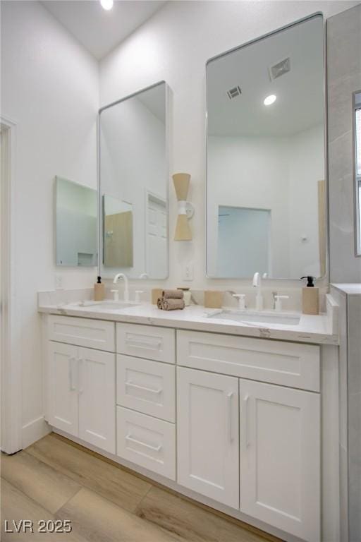 bathroom with double vanity, visible vents, and a sink