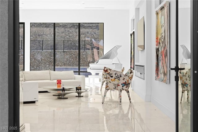 sitting room featuring a wealth of natural light, marble finish floor, and baseboards