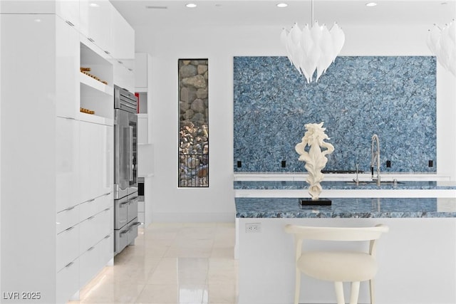 kitchen with light tile patterned floors, modern cabinets, a breakfast bar, white cabinetry, and pendant lighting