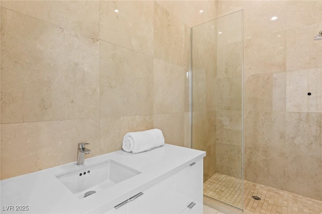 full bathroom featuring tile walls, a tile shower, and a sink