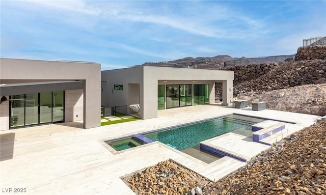 pool featuring an in ground hot tub, a patio, and a mountain view