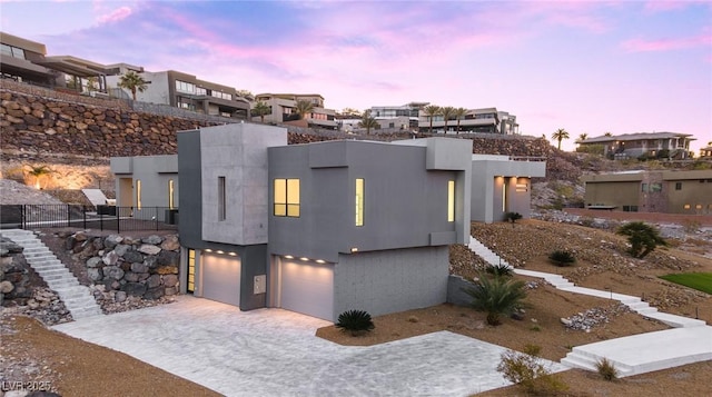 view of front of house with a garage, driveway, a residential view, and stucco siding