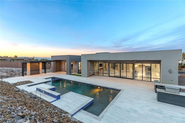 rear view of property with a patio area, stucco siding, fence, and an outdoor pool