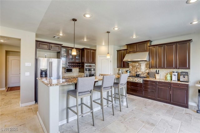 kitchen featuring pendant lighting, ventilation hood, stainless steel appliances, and a center island with sink