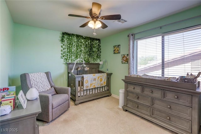 bedroom featuring ceiling fan, light colored carpet, and a crib