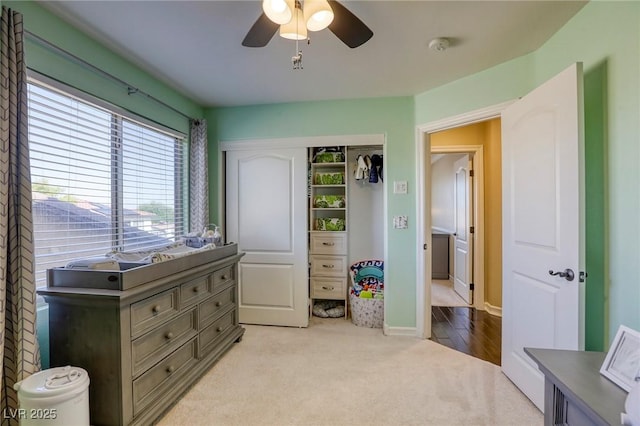 bedroom featuring light colored carpet, ceiling fan, and a closet