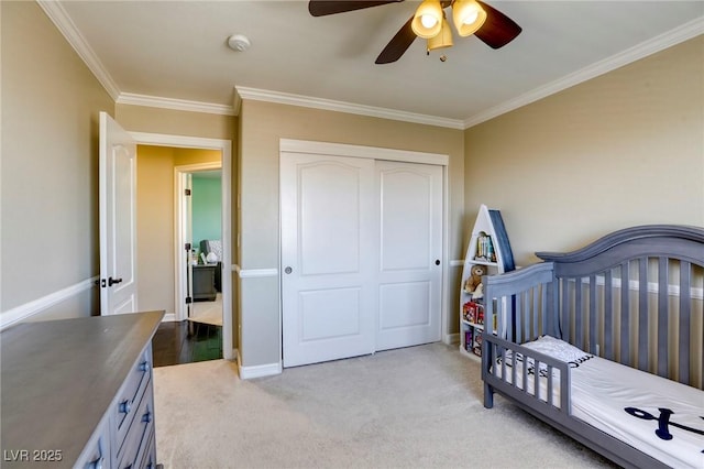 carpeted bedroom featuring ceiling fan, ornamental molding, and a closet