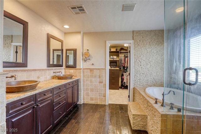 bathroom with hardwood / wood-style floors, vanity, tile walls, and plus walk in shower