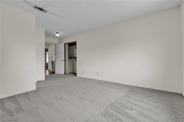 unfurnished room with baseboards, a textured ceiling, visible vents, and carpet flooring