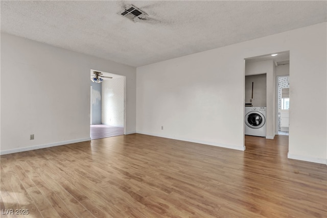 unfurnished room with light wood-style floors, washer / clothes dryer, visible vents, and a textured ceiling